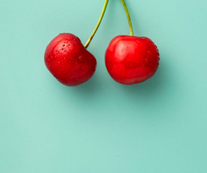 two strawberries hanging from a branch